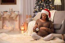 Happy Pregnant Woman With Christmas Ball At Home. Expecting Baby