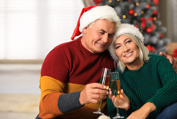 Wall Mural - Happy mature couple with glasses of champagne at home. Christmas celebration