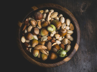 Wall Mural - nuts and seeds in a bowl on a dark brown wooden background in a dark key