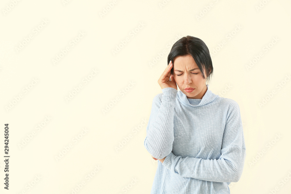 Portrait of woman suffering from headache on light background