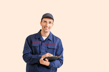 Wall Mural - Male car mechanic with clipboard on color background