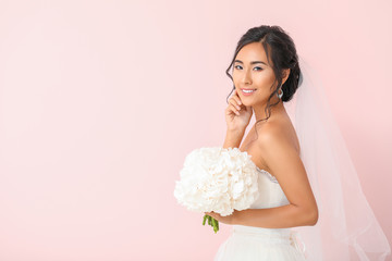 Beautiful young Asian bride on color background