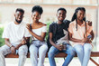 © F8  \ Suport Ukraine - Group of young african friends students hanging out together outdoors on a bench and laughing as they discuss