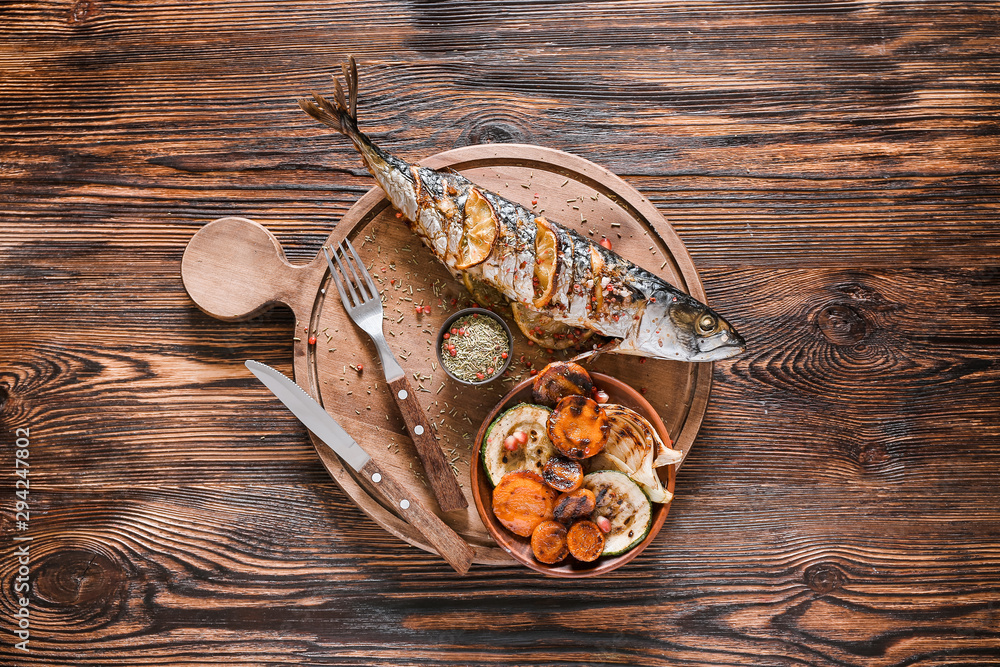 Board with prepared mackerel fish and vegetables on wooden background