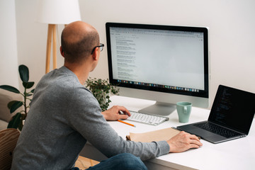 programmer, working behind the desk, googling and coding at the same time