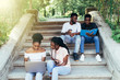 © F8  \ Suport Ukraine - Emotional african students looking excited in laptop, sitting outside on campus stairs, education.