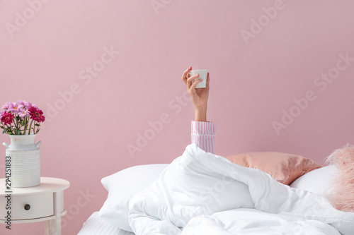 Fotomural Young woman with cup of coffee lying in bed