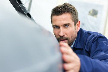 industrial automotive body worker inspecting the surface