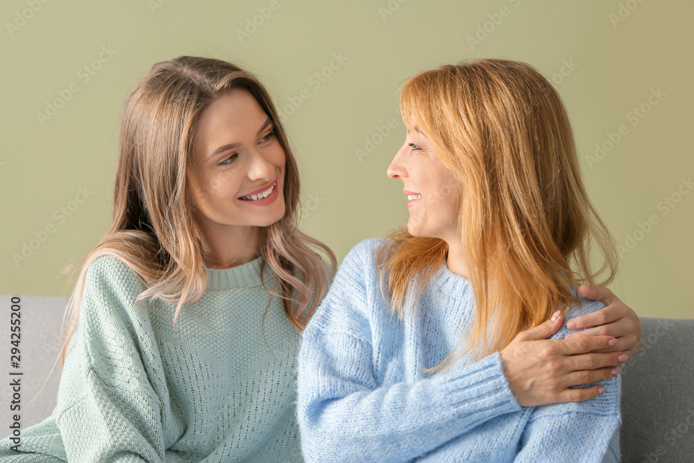 Happy mother and daughter sitting on sofa at home