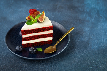 Wall Mural - A piece of delicious red velvet cake on a blue plate on dark background.