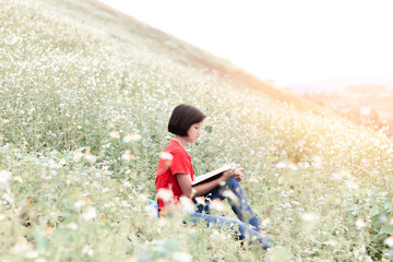 Canvas Print - Cute young girl reading book at park in summer