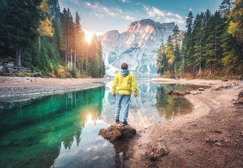 Wall Mural - man is standing on the stone on braies lake at sunrise in autumn. dolomites, italy. landscape with g
