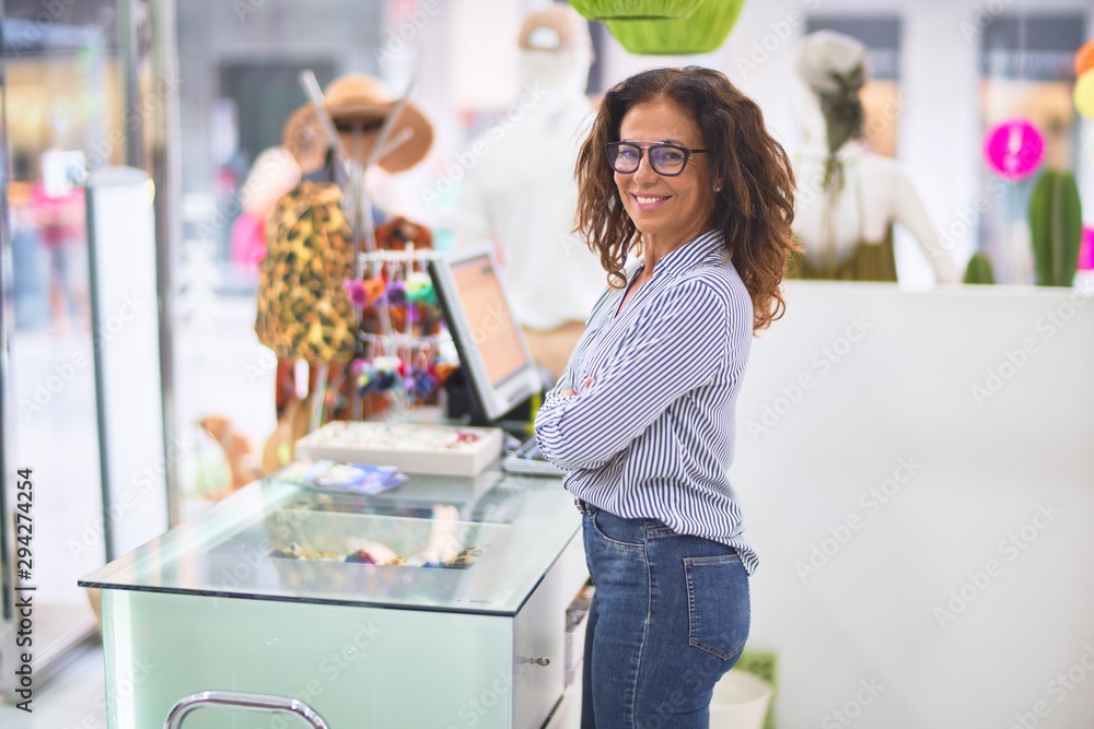 Middle age beautiful clothes shop owner woman smiling happy and confident waiting customers at counter