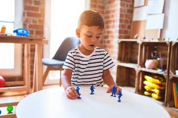 Beautiful toddler boy playing with figurine army soldiers at kindergarten