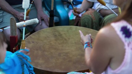 Wall Mural - Sacred drums at spiritual singing group. People are seen beating a mother drum with long drumsticks during a celebration of indigenous and shamanic music, seeking mindfulness and spirituality.