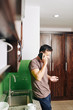 © DragonImages - Young man standing in kitchen with credit card in hand and talking on phone with bank manager or delivery service operator