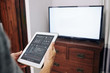 © DragonImages - Man using application on tablet computer to change channels and volume on tv set