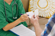 © DragonImages - Close-up image of nurse giving bottle with medicine and prescription note to senior patient