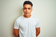© Krakenimages.com - Young brazilian man wearing t-shirt standing over isolated white background with serious expression on face. Simple and natural looking at the camera.