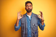 © Krakenimages.com - Handsome indian technician man wearing uniform over isolated yellow background relax and smiling with eyes closed doing meditation gesture with fingers. Yoga concept.