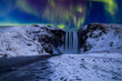 Skogafoss waterfall in the winter at night under the northern lights. Iceland.