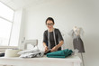 © satura_ - Dressmaker, fashion, tailor and people concept - young female fashion designer working in her showroom