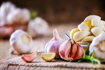 Wall Mural - Garlic cloves on wooden table with jute. Fresh garlic bulbs and peeled violet garlic and black pepper.