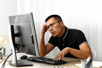 Asian programmer working on computer in office