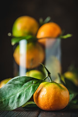 Wall Mural - Tangerines with leaves on an old fashioned country table. Selective focus. Vertical.