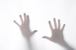 © Andrea - shadow or silhouette of two man's hands touching a white fabric from behind  in transparncy with copy space for your text