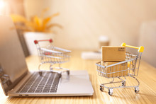 Online Shopping And Delivery Service Concept.Brown Paper Boxs In A Shopping Cart With Laptop Keyboard On Wood Table In Office Background.Easy Shopping With Finger Tips For Consumers.