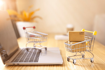 online shopping and delivery service concept.brown paper boxs in a shopping cart with laptop keyboar
