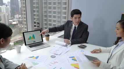 Wall Mural - Young Asian businessman presenting sales information to team in the meeting at the office in the city