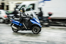A Motorcycle On Road In Big City. Motorbike Or Scooter On Three Wheels On Road In Motion.