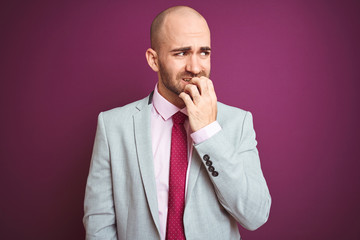 Wall Mural - Young business man wearing suit and tie over purple isolated background looking stressed and nervous with hands on mouth biting nails. Anxiety problem.