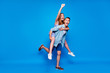 © deagreez - Full length body size view of two nice attractive overjoyed cheerful cheery glad positive people piggy-backing having fun fooling isolated on bright vivid shine vibrant blue color background