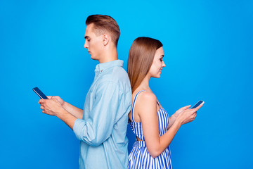 Wall Mural - Profile side view portrait of his he her she two nice attractive focused cheerful cheery people using device chatting isolated over bright vivid shine vibrant blue color background