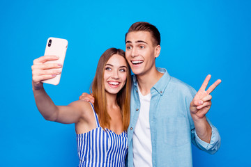 Portrait of his he her she two nice attractive lovely tender sweet cheerful cheery glad people embracing taking selfie showing v-sign isolated over bright vivid shine vibrant blue color background