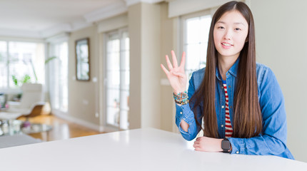 Sticker - Young beautiful asian woman with long hair wearing denim jacket showing and pointing up with fingers number four while smiling confident and happy.