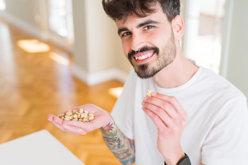 Young man eating pistachio, close up of hand with a bunch of healthy nuts