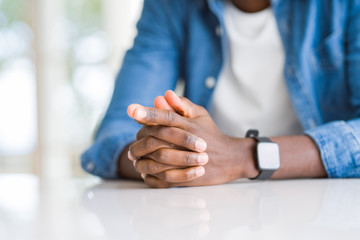 Canvas Print - Close up of crossed hands of african man over table