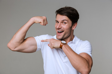 Sticker - Image of optimistic brunette man smiling and showing his bicep