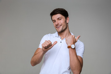 Sticker - Image of optimistic brunette man wearing basic t-shirt smiling and pointing fingers aside