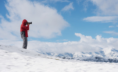 Wall Mural - a man taking photo on the snow with mountain view in winter
