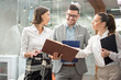 © Bojan - Business team discussing documents during an informal meeting in office lobby