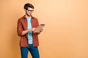 Portrait of his he nice attractive calm focused successful content brunet guy holding in hands reading digital e-book isolated over beige color pastel background