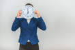 © Andrii - Funny young teacher in formal suit hiding her face behind a white clock.