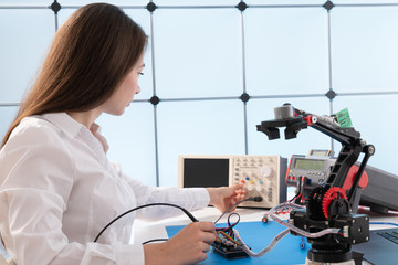 Sticker - A young woman writes an algorithm for the robot arm. Science Research Laboratory for Robotic Arm Model. Computer Laboratory