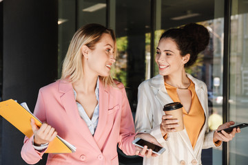 Wall Mural - Two beautiful young businesswomen walking outdoors