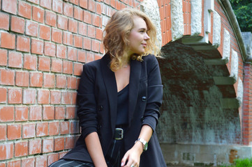 A sexy young woman in a business black suit is stands